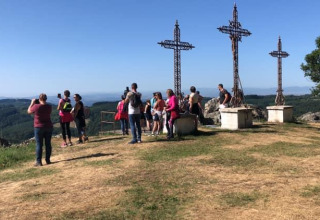 Turister tager billeder ved tre kors på en bakketop i Camping Paradis Les Chanterelles, Auvergne-Rhône-Alpes.