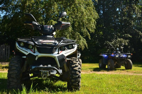 To ATV'er parkeret på græsplænen under træer i Camping Paradis Les Chanterelles, Auvergne-Rhône-Alpes, Frankrig.