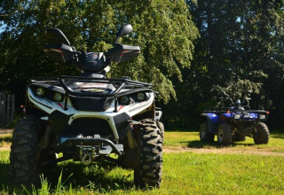 To ATV'er parkeret på græsplænen under træer i Camping Paradis Les Chanterelles, Auvergne-Rhône-Alpes, Frankrig.