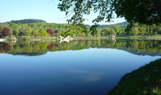 Paesaggio lacustre tranquillo vicino a Saint-Rémy-sur-Durolle in Auvergne-Rhône-Alpes, Francia, con riflessi d’alberi verdi.