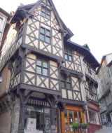 Un pittoresco edificio a graticcio su una via stretta con negozi a Saint-Rémy-sur-Durolle, Francia.