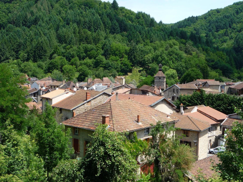Udsigt over Saint-Rémy-sur-Durolle med tage i terracotta og tæt skovklædt bakkelandskab i Frankrig.