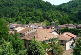 Udsigt over Saint-Rémy-sur-Durolle med tage i terracotta og tæt skovklædt bakkelandskab i Frankrig.