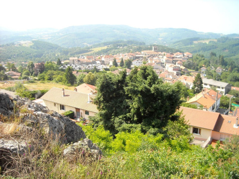 Udsigt over Saint-Rémy-sur-Durolle i Auvergne-Rhône-Alpes, Frankrig, med huse, træer og bjerge i baggrunden.