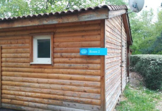 Vista esterna di un lodge in legno chiamato Roses 2 al Chalet Eco, Camping Paradis Les Chanterelles in Francia.
