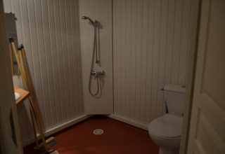 Salle de bain simple au Chalet Eco MIVA, Camping Paradis Les Chanterelles, avec douche, WC et matériel de nettoyage.