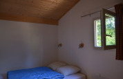 Una semplice camera da letto al Chalet Eco MIVA presso Camping Paradis Les Chanterelles in Francia con finestra aperta.