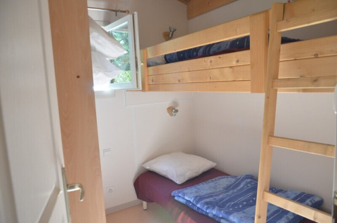 Petite chambre avec lits superposés en bois et fenêtre ouverte au Chalet Eco MIVA, Camping Paradis Les Chanterelles, France.