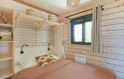 Lyst soveværelse på en lodge med træpaneler, enkeltseng, vindue, hylder og moderne indretning.