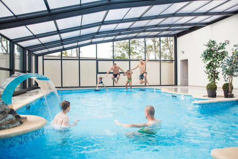 Piscine intérieure au Seasonova Camping Le Brabois, Grand Est, France, familles sautant et jouant dans l'eau.