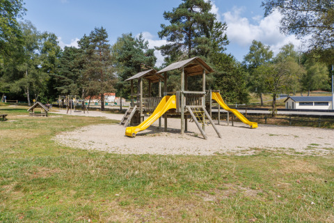 Spielplatz mit gelben Rutschen im Ferienpark Les Demeures du Lac in Auvergne-Rhône-Alpes, Frankreich.