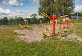 Buiten fitnessruimte met kleurrijke fitnesstoestellen bij Les Demeures du Lac in Frankrijk.
