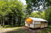 Tienda safari Maasaï Lodge en Seasonova Camping Le Brabois, Francia, rodeada de árboles verdes y naturaleza.