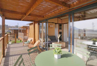 Casa tiny premium en Seasonova Camping Le Brabois, Francia, con terraza de madera y zona de estar exterior.