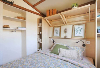 Dormitorio de una cabaña Premium en Seasonova Camping Le Brabois, Francia, con cama doble y estantes.
