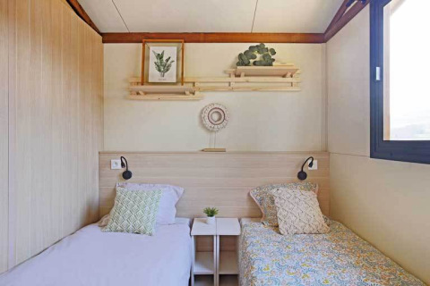 Habitación del Premium cottage con dos camas individuales y decoración acogedora en Seasonova Camping Le Brabois, Francia.