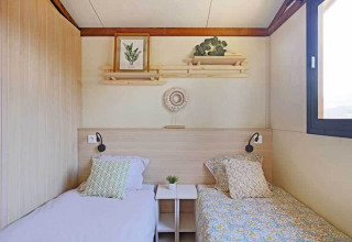 Habitación del Premium cottage con dos camas individuales y decoración acogedora en Seasonova Camping Le Brabois, Francia.