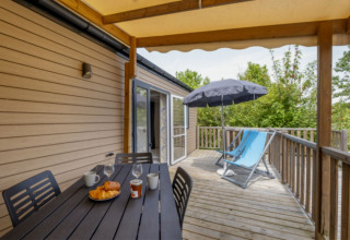 Wooden terrace with table, chairs, loungers, and parasol at Mobile home Comfort MIVA, Camping Le Plan d’Eau.