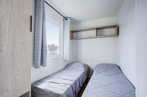 Slaapkamer met twee eenpersoonsbedden en een raam in Premium Mobile Home op Seasonova Camping Barberousse, Frankrijk.