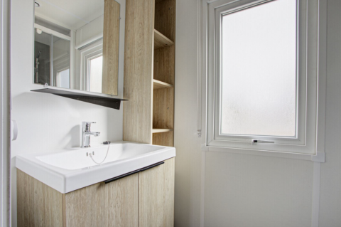 Moderne mobilhome badeværelse med lyst træskab, stor spejl og frostet vindue på Seasonova Camping Barberousse.