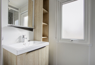 Moderne mobilhome badeværelse med lyst træskab, stor spejl og frostet vindue på Seasonova Camping Barberousse.