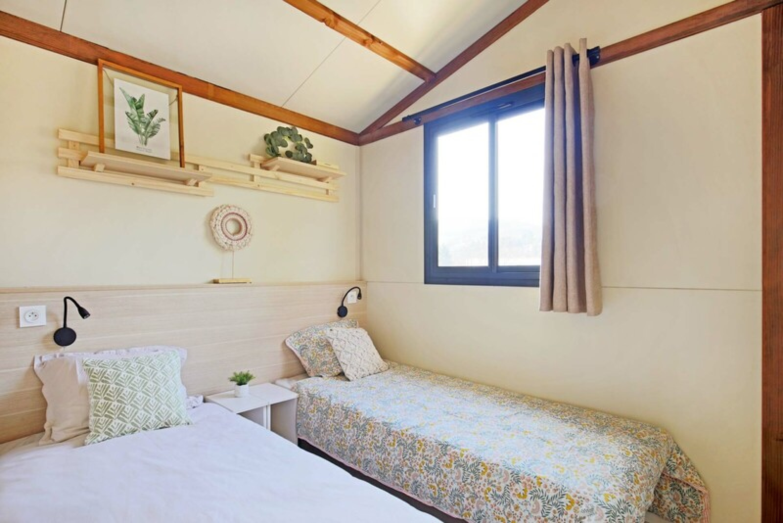 Gezellige tweepersoonskamer met lichte inrichting en raam in Cottage Comfort bij Camping Seasonova La Pointe de Roscoff, Frankrijk.