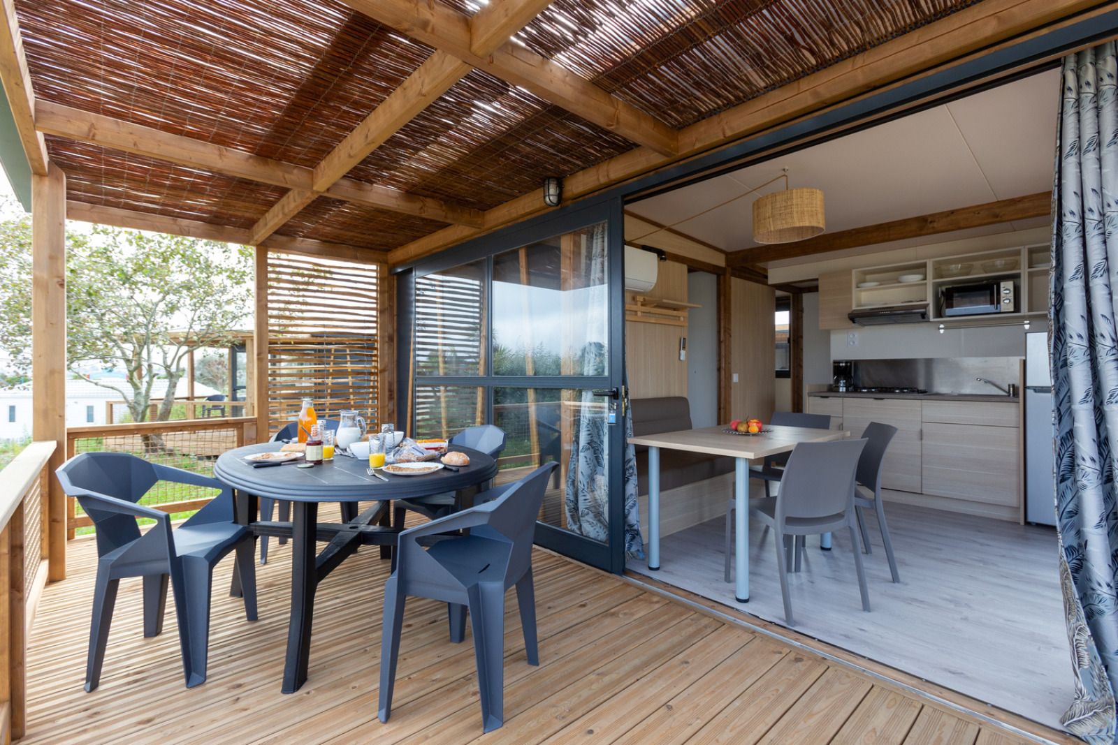 Houten terras met eettafel en modern interieur in Cottage Premium bij Camping Seasonova La Pointe de Roscoff, Frankrijk.