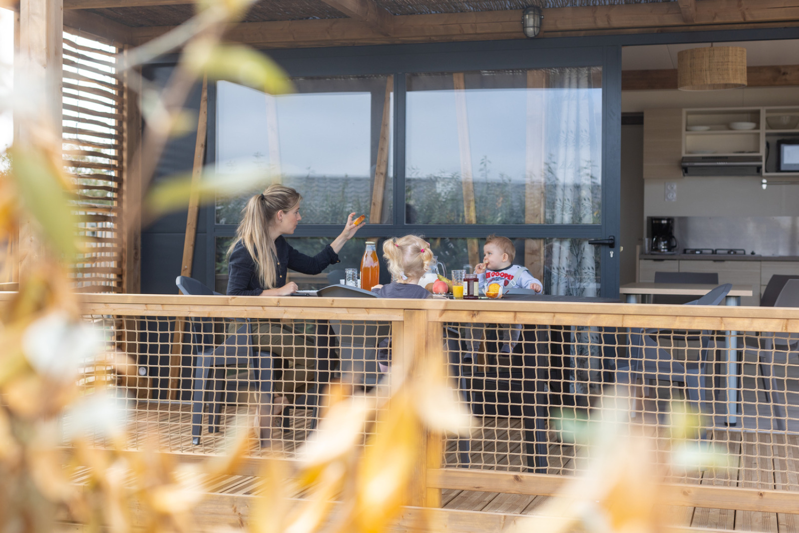 Een moeder en haar twee jonge kinderen ontbijten samen op het terras bij Cottage Premium, Camping Seasonova La Pointe de Roscoff.
