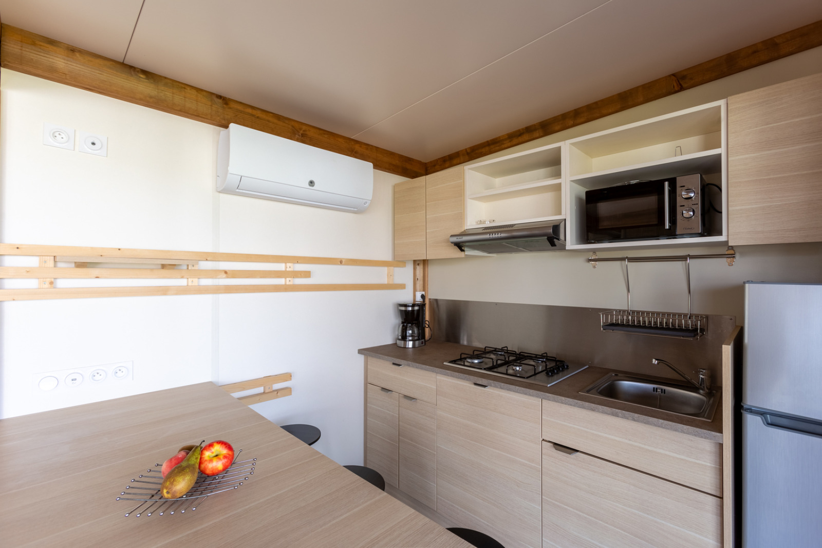 Moderne keuken in Premium Cottage van Camping Seasonova La Pointe de Roscoff, voorzien van apparatuur en fruit.