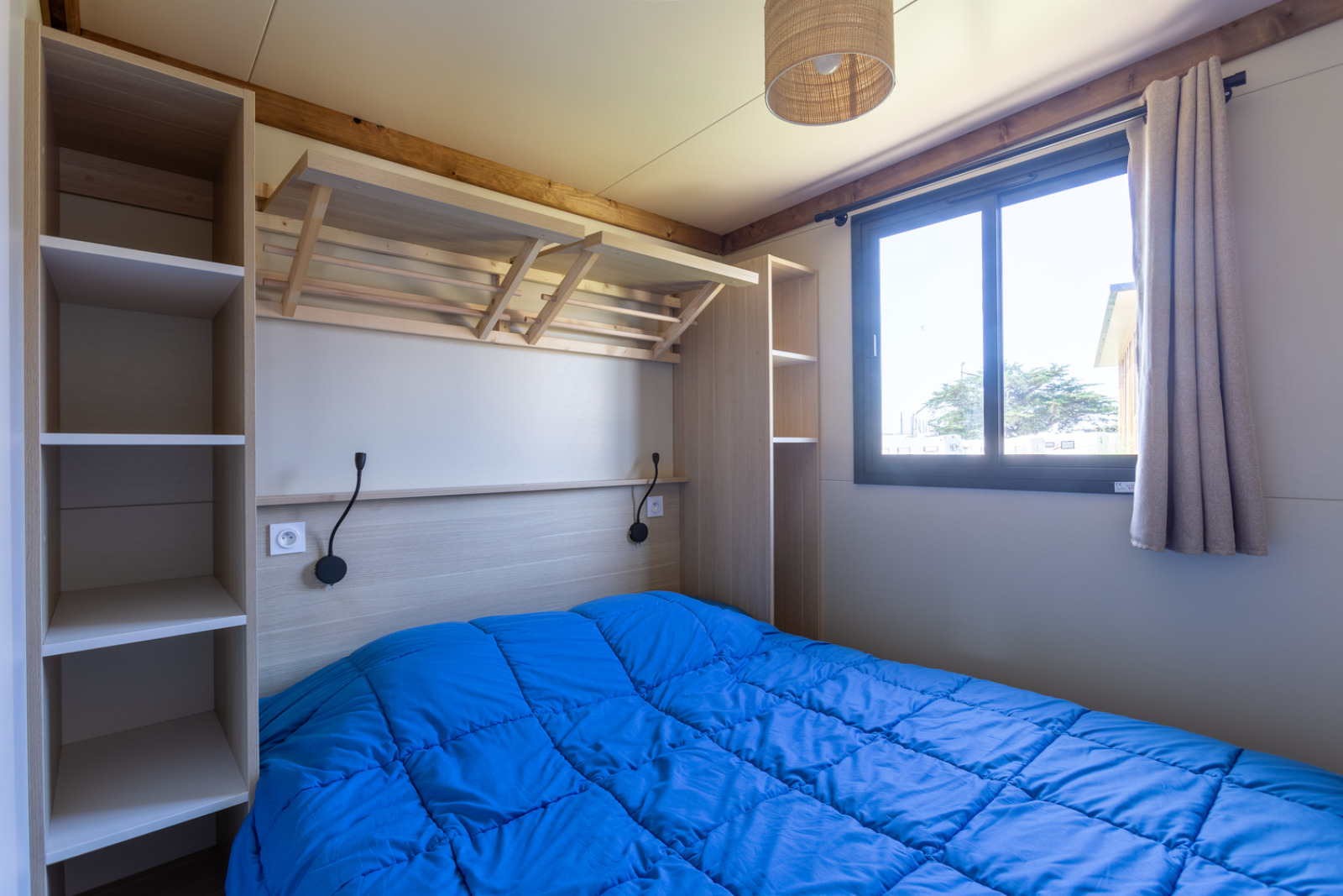 Moderne slaapkamer met een blauw dekbed in Premium Cottage, Camping Seasonova La Pointe de Roscoff, Frankrijk.