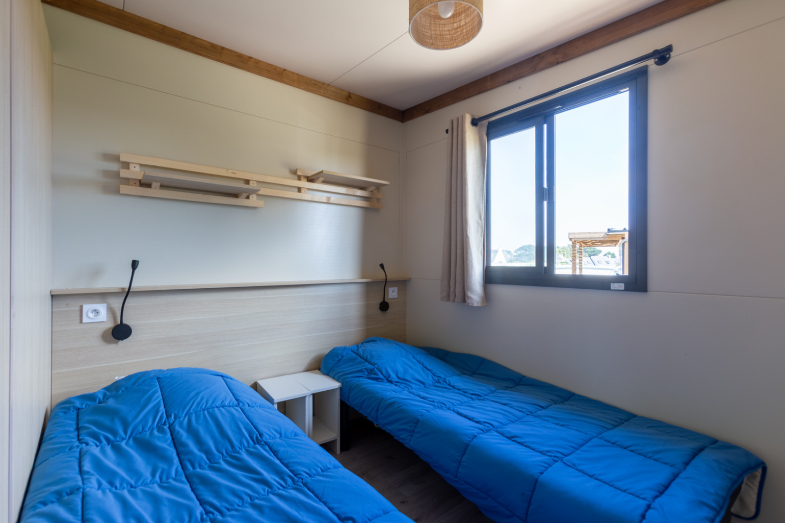 Moderne kamer met twee eenpersoonsbedden en blauwe dekbedden in Premium Cottage van Camping Seasonova La Pointe de Roscoff.