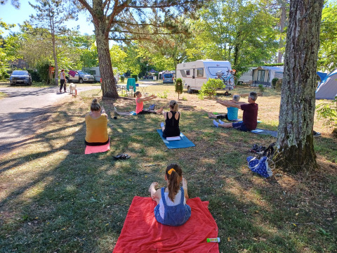 Des gens font du yoga sur l'herbe au camping Seasonova Le Lac de Cazaux à Occitanie, en France.
