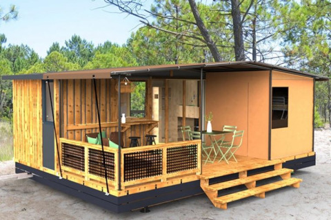 Kleine, moderne woning in het bos met houten veranda, buitenzitplaats en omringd door hoge bomen.