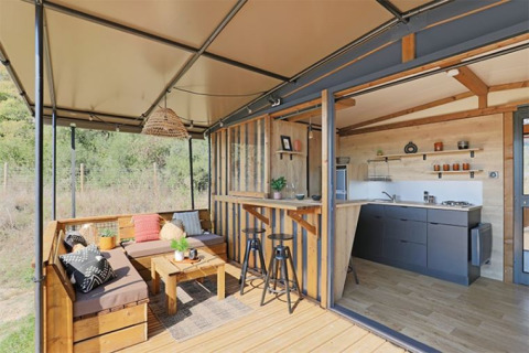 Tiny house met open keuken en gezellige zithoek buiten, houten meubels en warme moderne stijl.