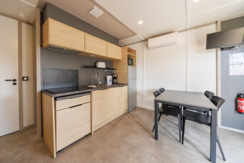 Moderne lodge-keuken met houten kasten, eettafel voor vier, airconditioning en wandgemonteerde tv.
