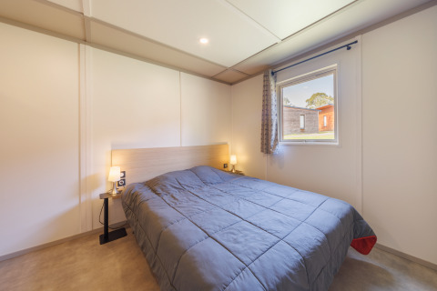 Gemütliches Schlafzimmer in einer Lodge mit Doppelbett, Nachttischen, Lampen und Fensterblick.
