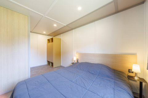 Modernes Schlafzimmer in einer Lodge mit großem Bett, Nachttischen, Lampen und minimalistischer Einrichtung.
