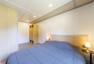 Moderne lodge soveværelse med en stor seng, natborde, lamper og minimalistisk indretning.