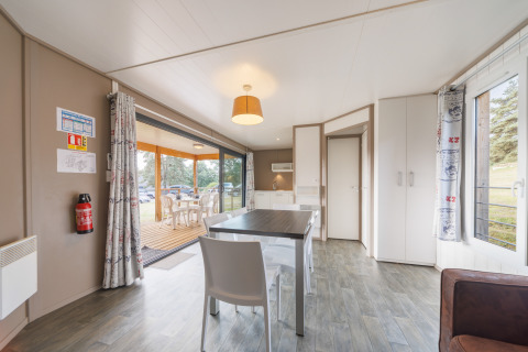Helle, moderne Lodge mit Essbereich, Aussicht auf eine Holzterrasse und großen Fenstern zur Natur.