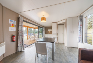 Helle, moderne Lodge mit Essbereich, Aussicht auf eine Holzterrasse und großen Fenstern zur Natur.
