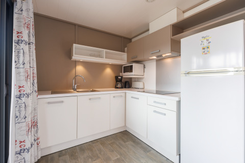 Moderne Küchenzeile in einer Lodge mit weißen Schränken, Herd, Spüle und großem Kühlschrank.