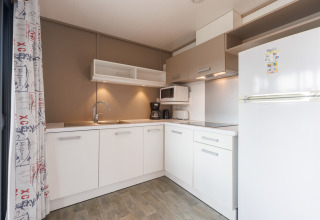 Moderne Küchenzeile in einer Lodge mit weißen Schränken, Herd, Spüle und großem Kühlschrank.