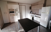 Moderne Küche im Cottage Premium des Camping Holiday Park Les Demeures du Lac mit Tisch und Geräten.
