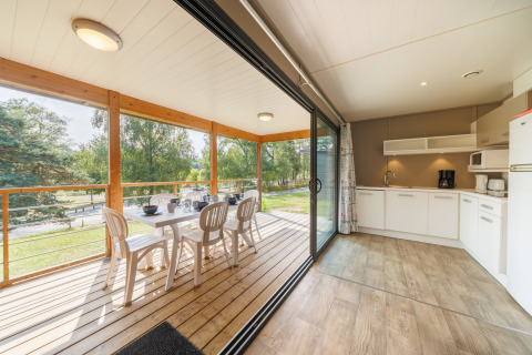 Helles Küchen- und Esszimmer mit Zugang zur überdachten Terrasse in einer Lodge, umgeben von Natur.