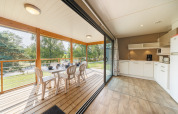 Helles Küchen- und Esszimmer mit Zugang zur überdachten Terrasse in einer Lodge, umgeben von Natur.