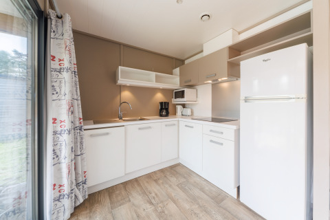 Cocina moderna de lodge con armarios blancos, suelo de madera, nevera grande y cafetera eléctrica.