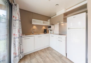 Cocina moderna de lodge con armarios blancos, suelo de madera, nevera grande y cafetera eléctrica.