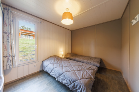 Chambre confortable dans un lodge avec deux lits simples, fenêtre avec vue et décoration moderne.