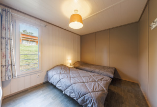 Gemütliches Schlafzimmer in einer Lodge mit zwei Einzelbetten, Fensterblick und moderner Dekoration.