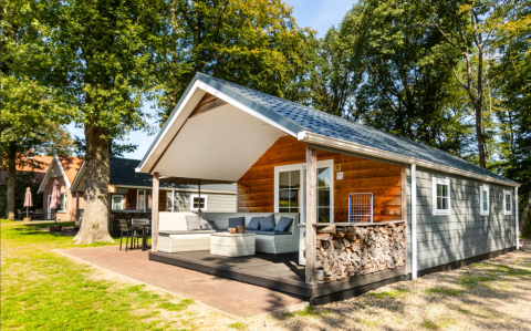 Modern wooden cabin at Campsite de Witte Berg in Overijssel, Netherlands, surrounded by trees in sunlight.